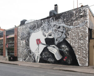 mural on side of building woman in mask with red rose